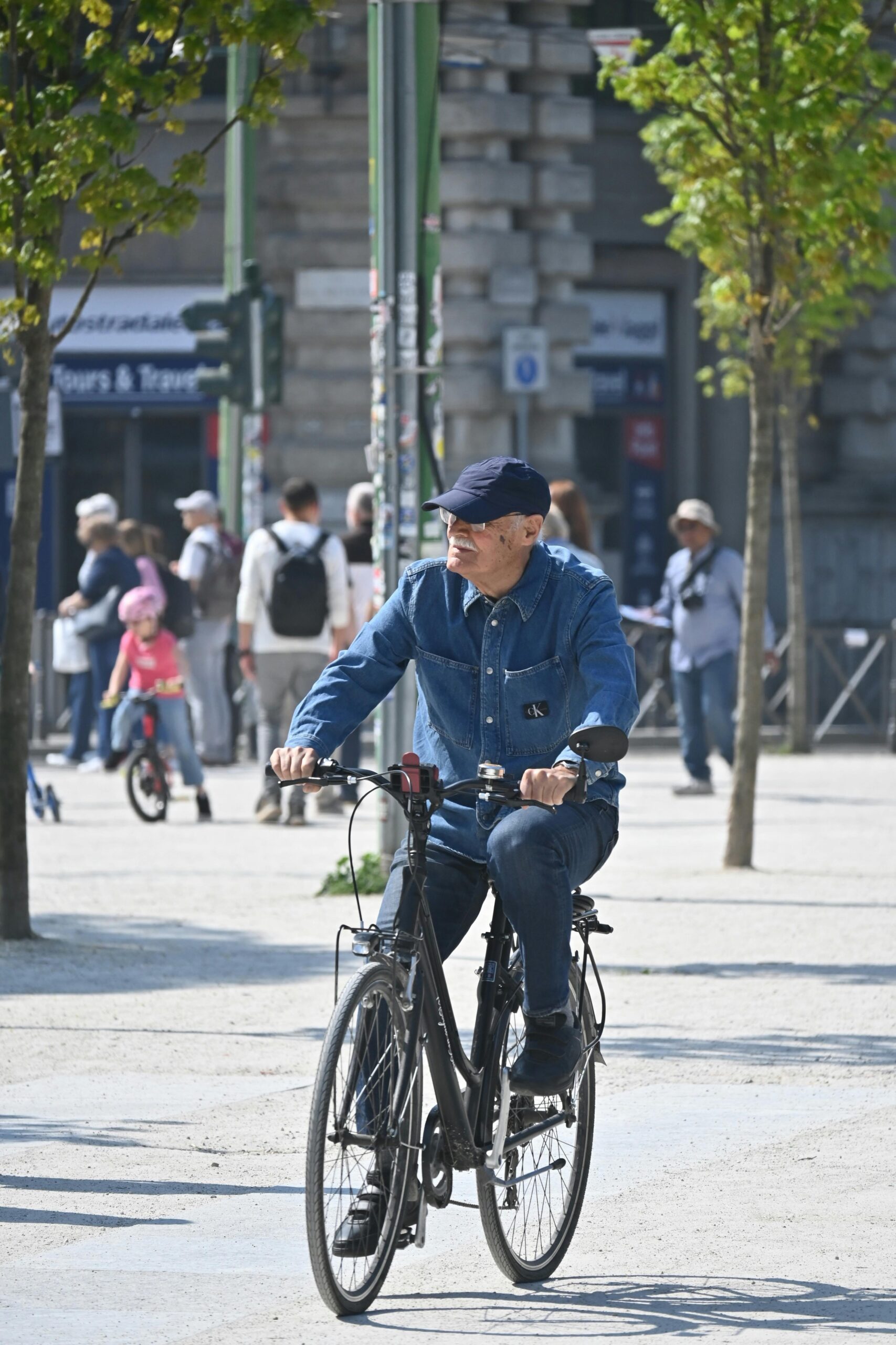 A senior man rides a bicycle in a city park on a sunny day, capturing active lifestyle.