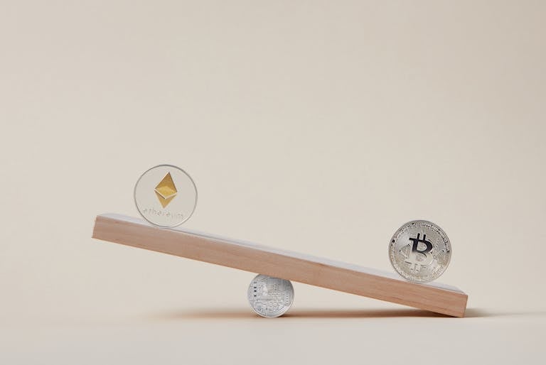 Minimalist image of Ethereum and Bitcoin coins balancing on a plank, symbolizing crypto market dynamics.