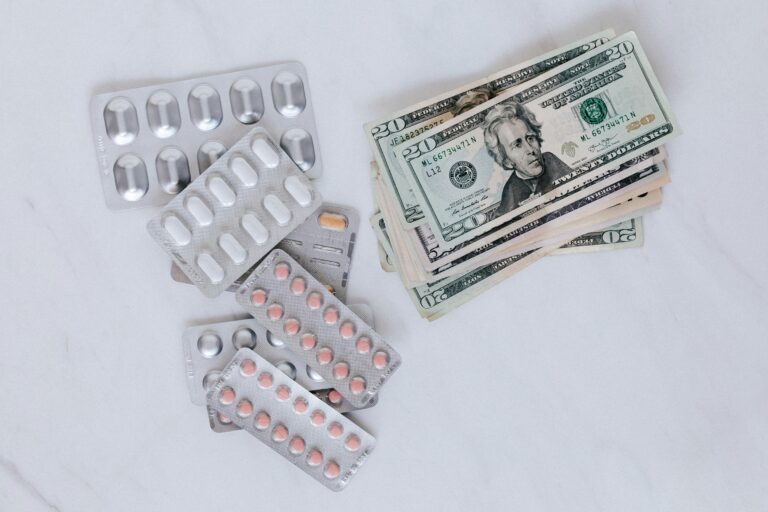 Blister packs of pills and US dollars on a white surface.