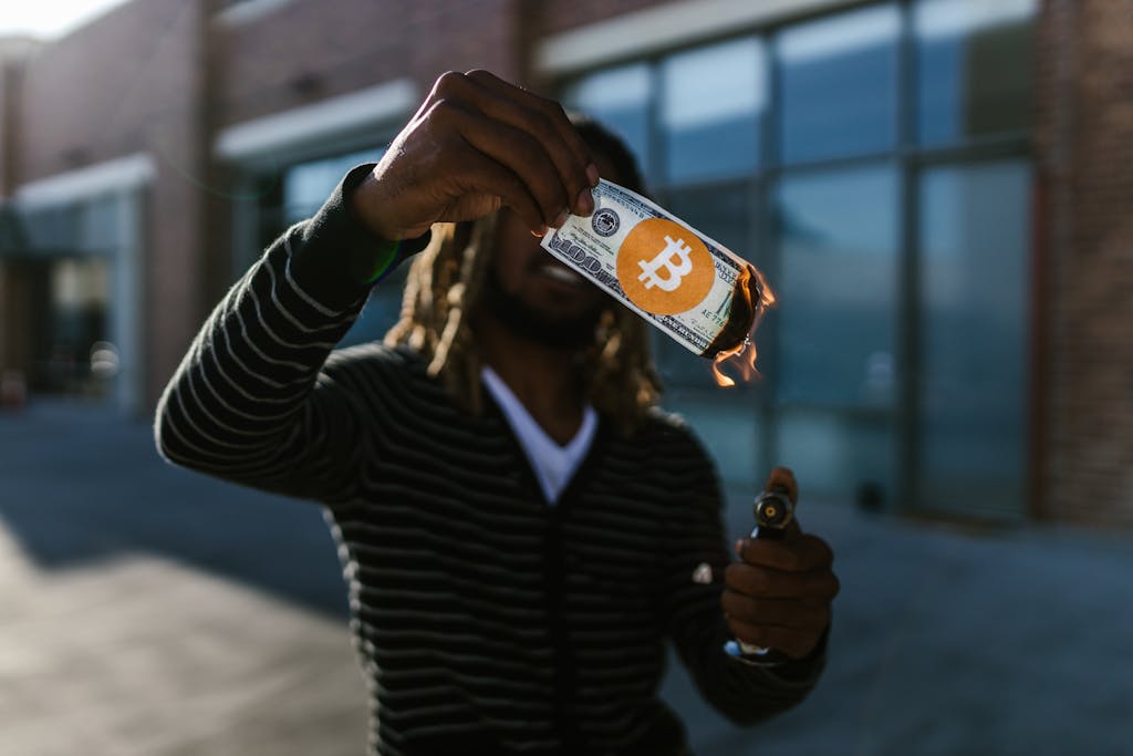 Man holding a burning dollar bill with Bitcoin symbol. Conceptual image of cryptocurrency impact.