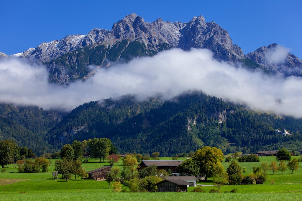 Stunning view of Alpine mountains with lush green valleys and scattered farmhouses.