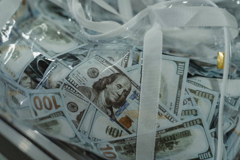 Close-up of transparent bag containing hundred dollar bills, symbolizing wealth.